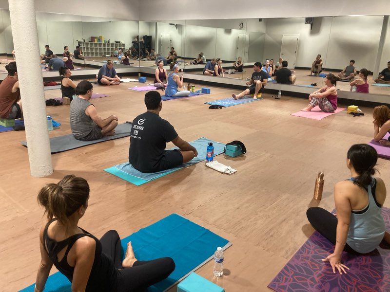 Studio Rental, Students sitting on the floor on yoga mats, in studio. For an instructional class.